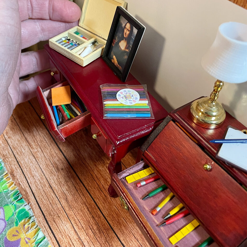 Two miniature desks with drawers open to reveal the tiniest pencils and notepads. 